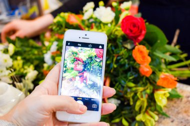 Çiçekçi buketin fotoğrafını çekiyor. Akıllı telefonunuzla çiçeklerin fotoğrafını çekiyorsunuz.