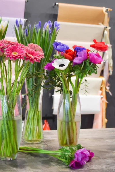 Una gran cantidad de hermosas flores en un jarrón de vidrio sobre la mesa. Las flores en la mesa vendiendo — Foto de Stock