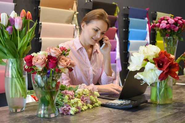 The florist accepts the flowers. Flower delivery. Florist girl at the Desk in the room — Stock Photo, Image