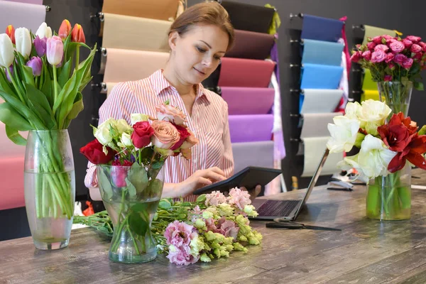 The florist accepts the flowers. Flower delivery. Florist girl at the Desk in the room — Stock Photo, Image
