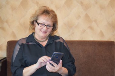 Ebeveynlerle mobil iletişim. Yetişkin bir kadın telefonda SMS mesajı yazar. Yaşlılar için internet aracılığı ile iletişim