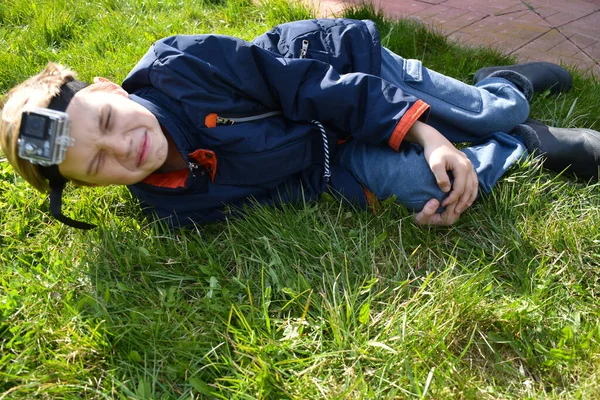 Anak itu terbaring di rumput dan berpegangan pada lutut. Bayi itu terluka kakinya — Stok Foto