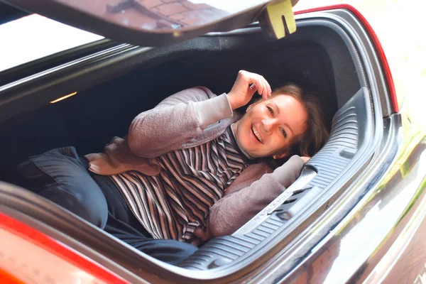 Une femme se trouve dans le coffre de la voiture. Fille gaie dans une voiture surprise — Photo