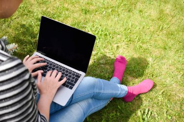 Bahçedeki çimlerin üzerinde serbest çalışan bir kadın. İnternette temiz havada çalışmak. Özgür yaşam