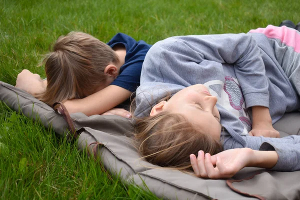 De kinderen slapen op een deken op het gazon. Broer en zus in slaap gevallen op een deken buiten — Stockfoto