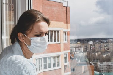 Zorunlu tecrit. Maskeli kadın üzgün görünüyor.