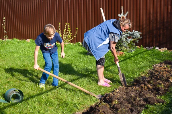 Mormor och sonson gräver jorden. Familj tillsammans vid stugan. — Stockfoto