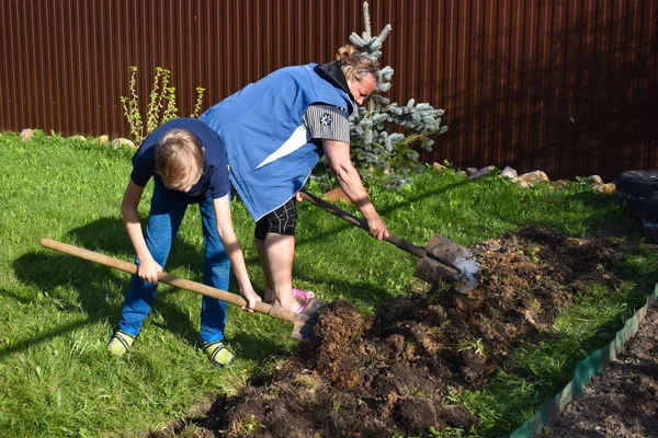 Mormor och sonson gräver jorden. Familj tillsammans vid stugan. — Stockfoto