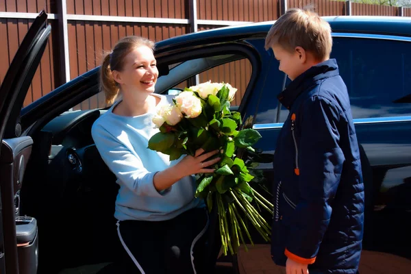 Fils donne un bouquet de roses à la mère. Mère heureuse avec enfant fils — Photo