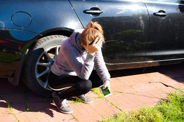 Jovem perturbada senta-se em uma estrada ao ar livre. ajuda de serviço de carro — Fotografia de Stock