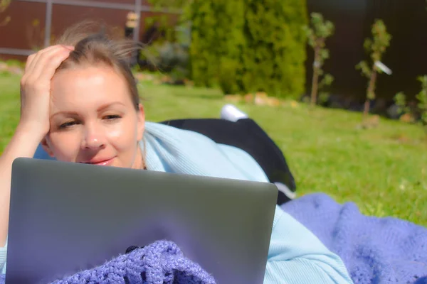 A comunicação na Internet. Mulher na grama com laptop olhando para a tela. Fique no jardim freelancer — Fotografia de Stock