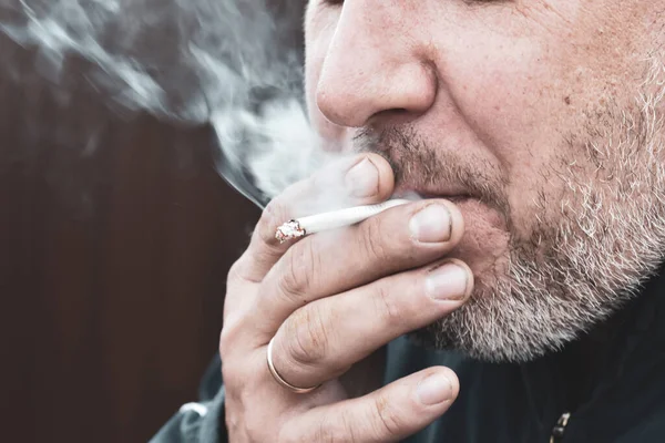 De schadelijkheid van het roken van sigaretten. Ruikende tabaksrook. Een man rookt. — Stockfoto