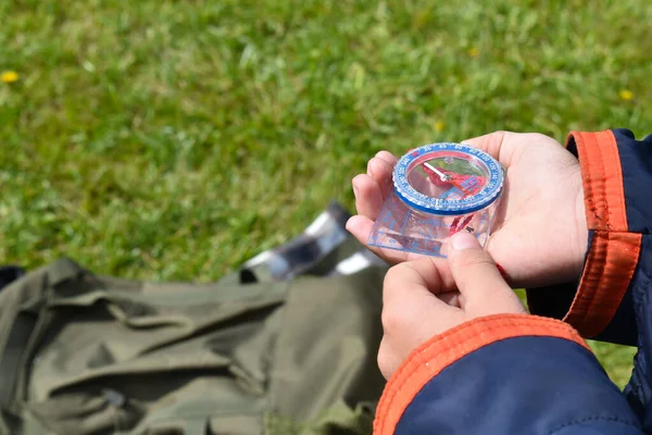 Kompass i handen på en barnresenär. Orientering. Vandrare pojke gå camping. — Stockfoto