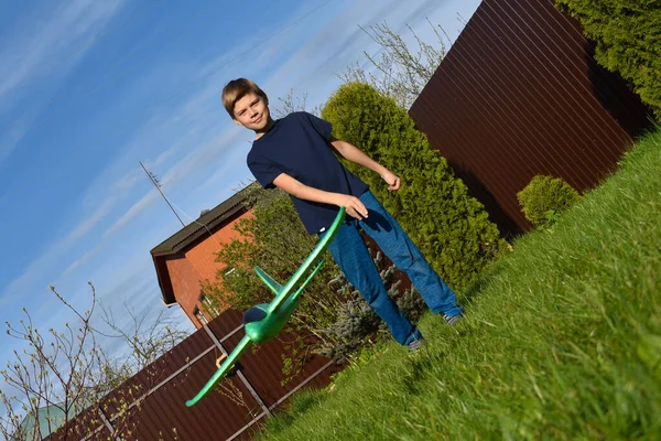 Enfant garçon jette un avion léger dans les airs. Des enfants jouent sur la pelouse. Petit garçon jouant dans le jardin — Photo