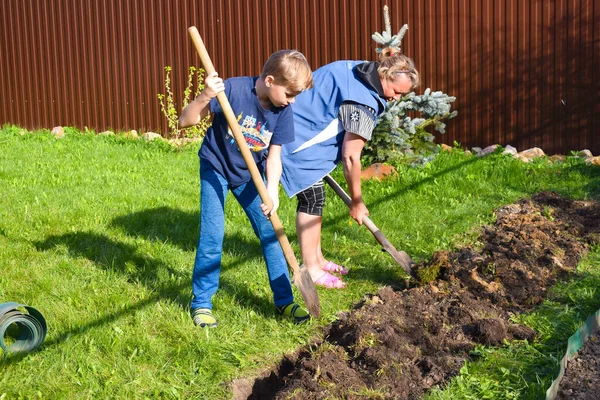 Mormor och sonson gräver jorden. Familj tillsammans vid stugan. — Stockfoto