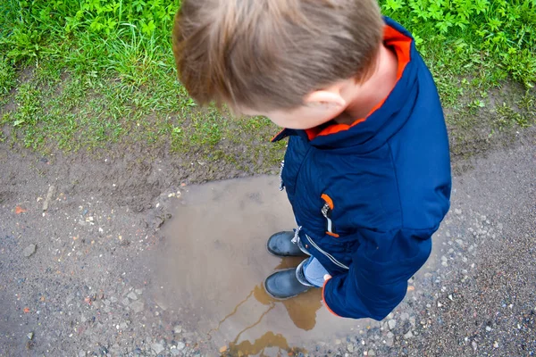 Village boy jumped. in a puddle on road. A happy childhood without the Internet — Stock Photo, Image