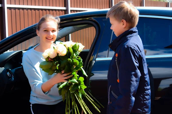 Fils donne un bouquet de roses à la mère. Mère heureuse avec enfant fils — Photo