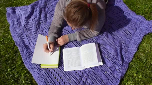 庭の毛布の上の女の子はレッスンを勉強します。遠隔学習屋外 — ストック動画
