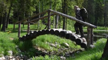 Turist elbiseli bir kadın yaz ormanlarında yalnız seyahat eder. tahta kütük köprüsü.