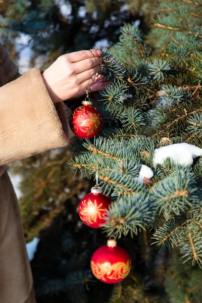 Женщина вешает рождественские украшения на елку крупным планом . — стоковое фото