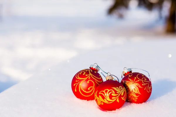 Drie rode kerstballen op een sneeuw. — Stockfoto