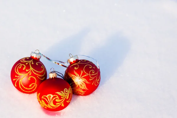 Drie rode kerstballen op een sneeuw. — Stockfoto
