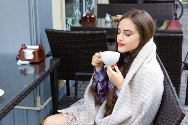 Hermosa chica envuelta en manta sosteniendo una taza de té — Foto de Stock