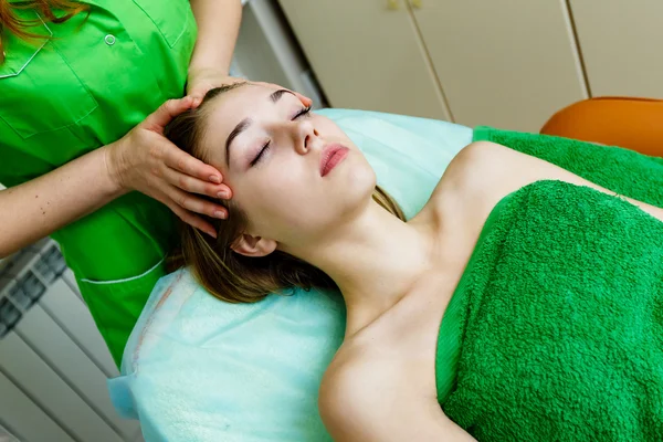 Young caucasian girl getting a face massage in spa salon — Stock Photo, Image