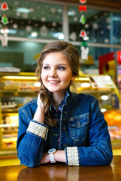 Hermosa chica sonriente con el pelo largo y rubio sentado en la cafetería — Foto de Stock