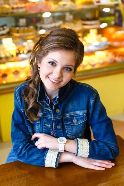 Hermosa chica sonriente con el pelo largo sentado en la cafetería — Foto de Stock