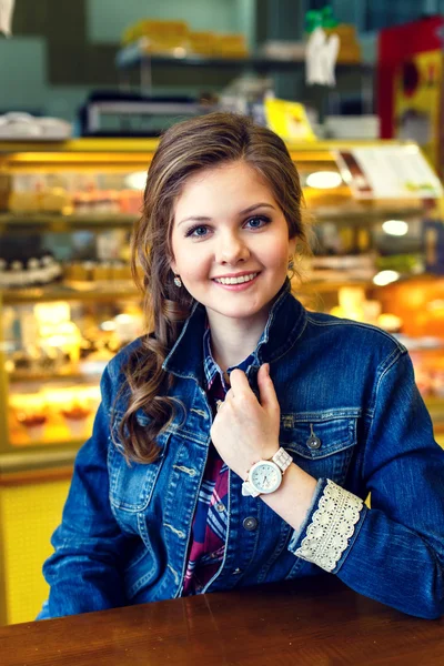 Красивая улыбающаяся девушка с длинными волосами сидит в кафе Стоковая Картинка