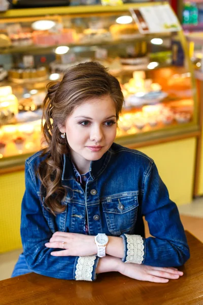 Красивая улыбающаяся девушка с длинными светлыми волосами сидит в кафе Стоковое Фото