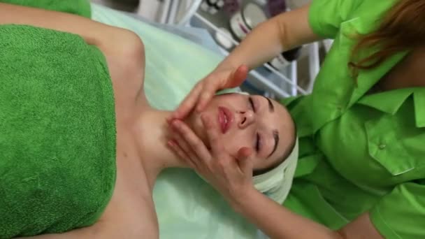 Joven mujer caucásica recibiendo un masaje facial en el salón de spa — Vídeo de stock