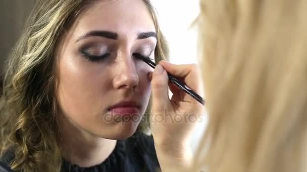 Maquillaje artista hacer maquillaje de una hermosa joven — Vídeos de Stock