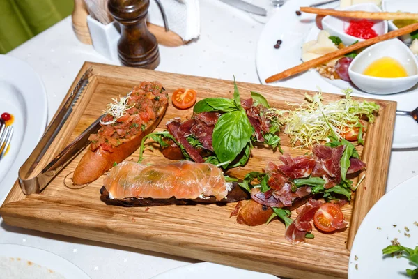 Antipasti di pesce e carne su piatto di legno in ristorante — Foto Stock