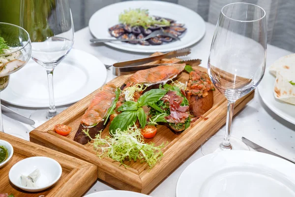 Předkrmy z mořských plodů a masa na dřevěné desce v restauraci — Stock fotografie
