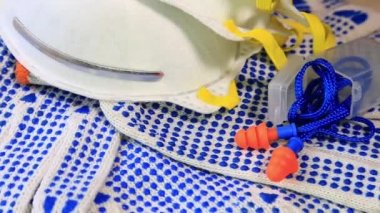 Mavi sivilce, solunum maskeleri ve kulak tıkacı dönen bir yüzey üzerinde ince iş eldivenleri, 