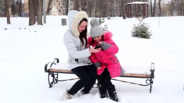 İki kız, anne ve kızı, kar kış soğuk günde bir parkta atma.