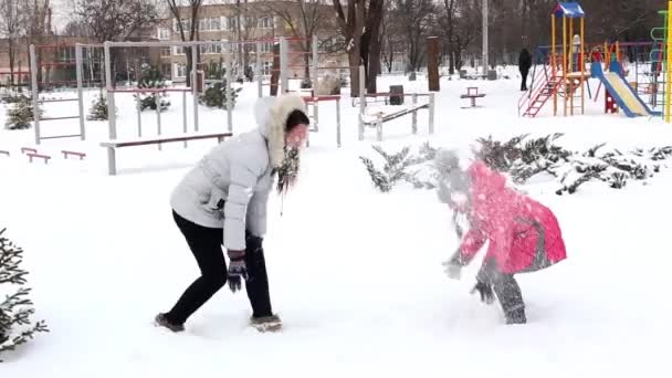 Dvě dívky, matka a dcera, hraje sníh v parku v zimní mrazivý den. — Stock video