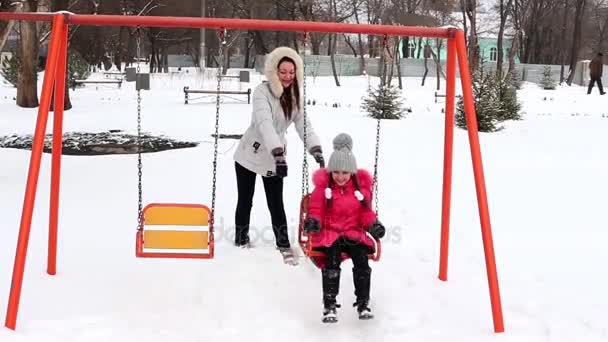Μητέρα και κόρη σε μια ταλάντευση στο πάρκο σε ψυχρός ημέρα του χειμώνα. — Αρχείο Βίντεο