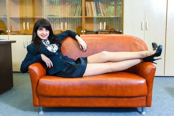 Молода красива бізнес-леді лежить на дивані в офісі — стокове фото
