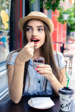 Kırsal şapkalı güzel genç kız yaz günü açık hava kafede kek yiyor..