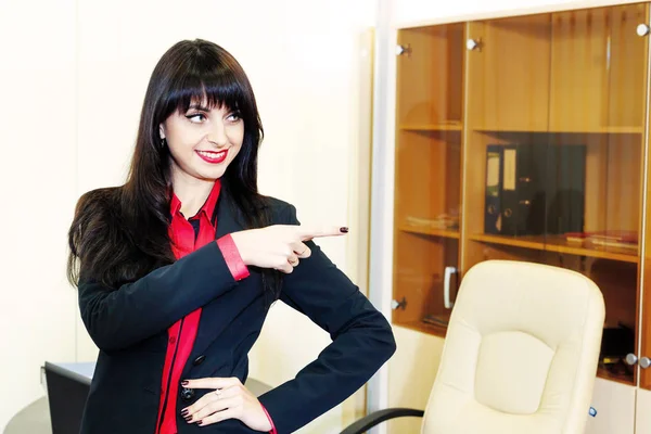 Smiling young businesswoman shows a finger in the direction. — Stock Photo, Image