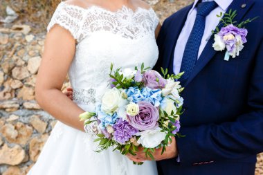 Gelin ve damat güzel gül buketi açık havada tutan.