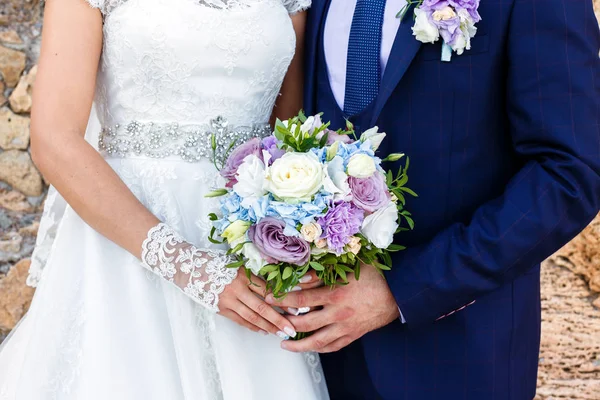 Gelin ve damat güzel gül buketi açık havada tutan.