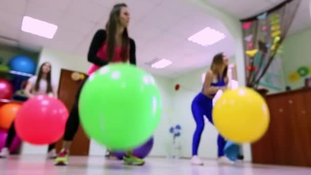 Un grupo de mujeres jóvenes haciendo ejercicios con pelotas de fitness en un gimnasio . — Vídeos de Stock