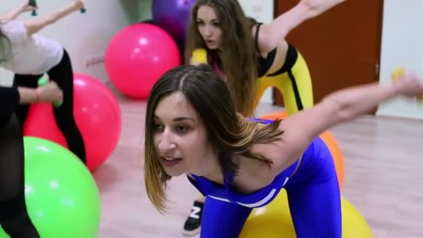 Groep jonge Kaukasische vrouwen doen oefeningen met fitballs in een fitnessclub. — Stockvideo