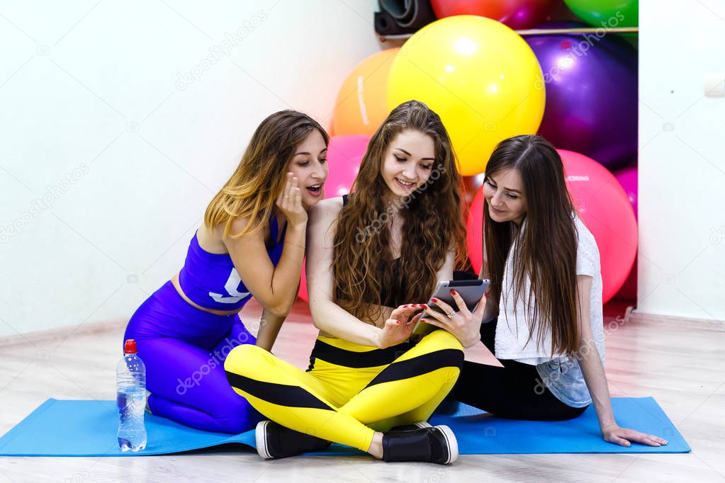 Group of young cheerful caucasian women using tablet PC in a fit
