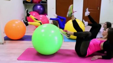 Bir grup genç beyaz kadın fitness Club bir katta döşeme fitballs ile egzersizleri yapıyor. 