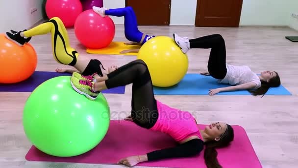 Um grupo de mulheres caucasianas jovens que fazem exercícios com fitballs que põem em um soalho em um clube de fitness . — Vídeo de Stock